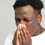 close-up-studio-portrait-of-young-african-man-with-napkin-sneezing-isolated-on-grey-white-background_t20_E0k6n1-112606_1047x675